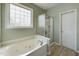 Relaxing bathroom with a jetted tub, glass-enclosed shower, and window for natural light, offering a spa-like experience at 3705 Andoversford Ct, Wake Forest, NC 27587