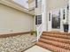 Inviting entrance with brick steps, white railing, rock landscaping, and a storm door at 3705 Andoversford Ct, Wake Forest, NC 27587