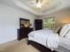 Bright bedroom features a tray ceiling, natural light from a window, and well-placed dresser with a mirror at 3705 Andoversford Ct, Wake Forest, NC 27587
