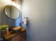Stylish powder room featuring a unique vessel sink, wooden vanity, round mirror, and modern faucet fixtures at 3705 Andoversford Ct, Wake Forest, NC 27587