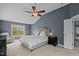 This bedroom features blue walls, a ceiling fan, a large window, and an upholstered bed at 3725 Song Sparrow Dr, Wake Forest, NC 27587
