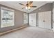 Comfortable bedroom with neutral carpet, ceiling fan, and ample natural light from the large windows at 408 Teal Lake Dr, Holly Springs, NC 27540