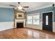 Bright living room with a fireplace, hardwood floors, and large windows offering neighborhood views at 408 Teal Lake Dr, Holly Springs, NC 27540