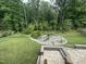 Beautiful backyard featuring a lush lawn, landscaped garden bed, and a stone patio for outdoor enjoyment at 420 Cahors Trl, Holly Springs, NC 27540