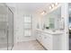 Bright bathroom with double sink vanity, large mirror, tiled floors, and glass-enclosed shower at 420 Cahors Trl, Holly Springs, NC 27540