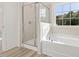 Bright bathroom features a tiled shower, a soaking tub beneath a large window, and neutral decor at 426 Adams Pointe Ct, Angier, NC 27501