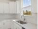 Kitchen with stainless steel sink, faucet, white cabinets, and view of the backyard at 426 Adams Pointe Ct, Angier, NC 27501