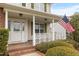 Welcoming front porch with classic columns, American flag, and lush landscaping, enhancing the home's appeal at 43 Summerseat Way, Bunnlevel, NC 28323