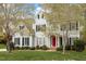 Beautiful two-story home with lush lawn, red door entry, and traditional shutters is framed by mature trees at 4313 Branchwood Dr, Durham, NC 27705