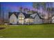 Manicured backyard featuring a modern farmhouse, lush lawn, and mature trees at 472 Stonecrest Way, Pittsboro, NC 27312