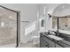 Stylish bathroom features a tiled walk-in shower, dark vanity with granite countertop and arched mirror at 472 Stonecrest Way, Pittsboro, NC 27312