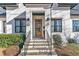 Inviting front entrance with a stylish wooden door, black sconces and stone steps at 472 Stonecrest Way, Pittsboro, NC 27312