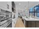 Modern kitchen featuring stainless steel appliances, white cabinets, and a large island with marble countertops at 472 Stonecrest Way, Pittsboro, NC 27312