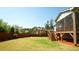 Large grass backyard featuring a wood fence, landscaping, and a porch with stairs at 504 Prince Dr, Holly Springs, NC 27540