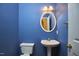 Cozy blue half bath with white toilet and pedestal sink, decorative mirror, and brass fixtures at 5612 Crossfield Dr, Raleigh, NC 27613