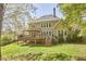 Back of house showing the raised deck, stairs, windows, and chimney with trees in the background at 5612 Crossfield Dr, Raleigh, NC 27613