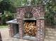 Close up of brick pizza oven with a full load of firewood below the oven in a tranquil backyard space at 6020 Jones Farm Rd, Wake Forest, NC 27587