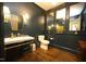 Stylish powder room with dark blue walls, marble vanity, gold fixtures and hardwood floors at 620 Wade Ave # 206, Raleigh, NC 27605