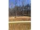 A view of a large backyard with a pile of dirt surrounded by a forest with a wood railing in the foreground at 70 Valebrook Ct, Youngsville, NC 27596