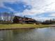Beautiful exterior view of a lodge-style home situated on a grassy lawn with a pond in front at 70 Valebrook Ct, Youngsville, NC 27596