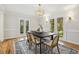 Bright dining room with hardwood floors, decorative chandelier, and access to backyard through french doors at 8008 Hollander Pl, Raleigh, NC 27606