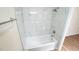 White tiled tub and shower combination with chrome fixtures in updated bathroom at 909 Windcrest Rd, Durham, NC 27713