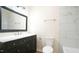 Bathroom featuring a black vanity with marble countertop, mirror and tiled tub and shower at 909 Windcrest Rd, Durham, NC 27713