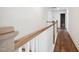 Upstairs hallway featuring luxury vinyl flooring and a wood and white banister overlooking a spacious open area at 9512 Wood River Dr, Zebulon, NC 27597