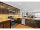 Modern kitchen with stainless steel appliances, granite countertops, and dark wood cabinetry at 989 Ambergate Sta, Apex, NC 27502