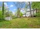 Spacious backyard with lush green grass, mature trees, a storage shed, and a view of the two-story home at 1003 Buckhorn Rd, Garner, NC 27529