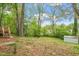 A verdant backyard featuring mature trees, a wooden deck with stairs, and a storage shed at 1003 Buckhorn Rd, Garner, NC 27529