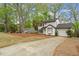 Traditional house with white siding, black shutters, an attached garage and long driveway surrounded by mature trees at 1003 Buckhorn Rd, Garner, NC 27529