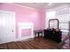 Bright bedroom featuring a pink wall, fireplace and gleaming hardwood floors at 10095 N Walnut St St, Middlesex, NC 27557