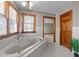 Bright bathroom featuring a large soaking tub, tile surround, and a natural wood door at 104 Stage Line Cv, Louisburg, NC 27549