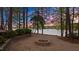 Outdoor fire pit with stone surround near the lake and surrounded by mature trees at 104 Stage Line Cv, Louisburg, NC 27549