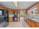 Well-lit kitchen with black appliances, wood cabinets, granite counters, and tiled floors at 104 Stage Line Cv, Louisburg, NC 27549