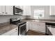 Bright kitchen features stainless steel appliances, granite countertops, white cabinets and wood floors at 109 Wyeth Meadows Ln, Holly Springs, NC 27540