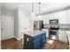 Bright kitchen features stainless steel appliances, white cabinets and a blue island with granite countertop at 109 Wyeth Meadows Ln, Holly Springs, NC 27540