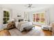 Sun-filled main bedroom featuring many windows, a ceiling fan, hardwood floors, and ensuite bathroom at 125 Dartmoor Ln, Raleigh, NC 27614