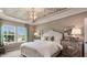 Bright main bedroom showcasing a bed with white linens, decorative pillows, and complemented by a unique ceiling fixture at 1260 Hazelnut Ridge Ln, Knightdale, NC 27545