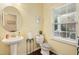 Bright half bathroom with a pedestal sink, decorative mirror, and natural light from the window at 1620 Frog Hollow Way, Wake Forest, NC 27587