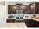 Bright kitchen featuring stainless steel appliances, dark wood cabinetry, granite countertops and tile backsplash at 1620 Frog Hollow Way, Wake Forest, NC 27587