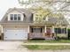 Charming home featuring a welcoming front porch, manicured lawn, and an attached two-car garage at 1625 Heritage Garden St, Wake Forest, NC 27587