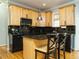 Well-lit kitchen features wood cabinets, black appliances and countertops, and an island with bar stool seating at 1625 Heritage Garden St, Wake Forest, NC 27587