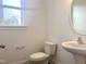 Bathroom with a pedestal sink, toilet, and a window providing natural light at 176 Golfview Ave, Benson, NC 27504