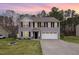 Charming two-story home featuring a well-maintained lawn and a two-car garage at dusk at 211 Richmond Run, Stem, NC 27581