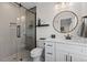 Modern bathroom with glass-enclosed shower, white vanity, and round mirror with gold trim at 2207 Otis St # A, Durham, NC 27707