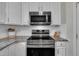 Stainless steel stovetop and oven in a kitchen with granite countertops and white cabinets at 2832 Steeple Run Dr, Wake Forest, NC 27587