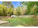 Large fenced backyard with mature trees, lush green grass, and a storage shed at 3332 Apache Dr, Raleigh, NC 27609