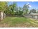 View of the expansive, fenced backyard with lush lawn, mature trees, and patio space at 3332 Apache Dr, Raleigh, NC 27609